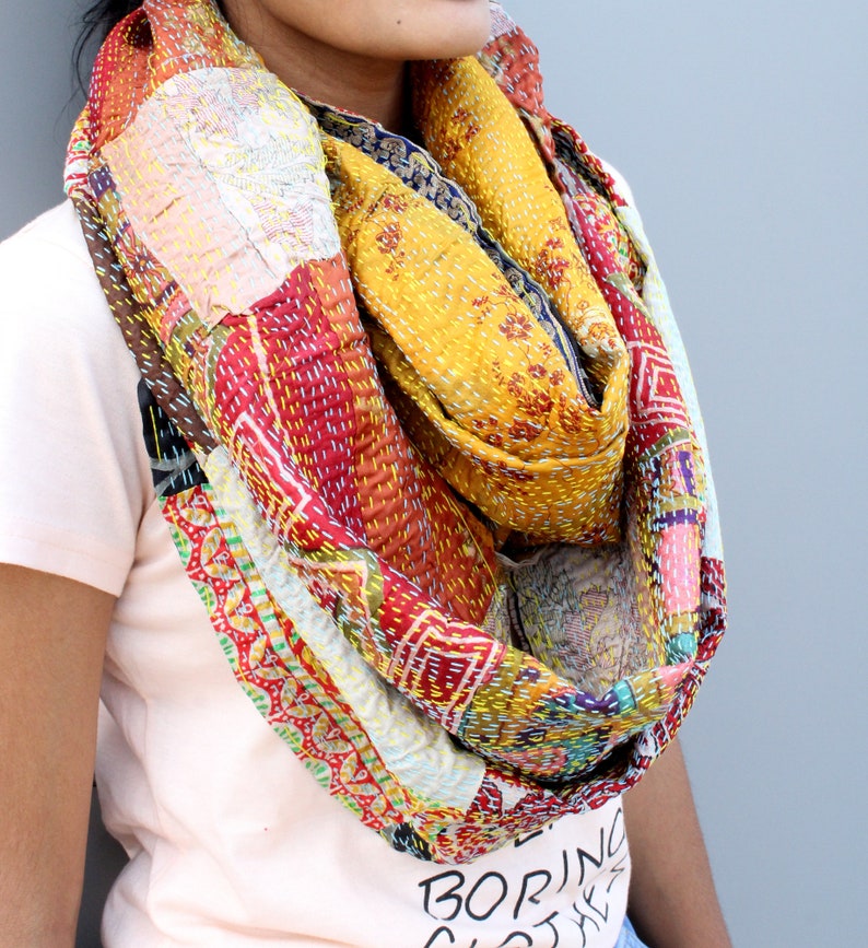 May include: A colourful patchwork scarf made from recycled saris. The scarf is a mix of red, yellow, blue, and green fabrics with intricate embroidery. It is a unique and stylish accessory.