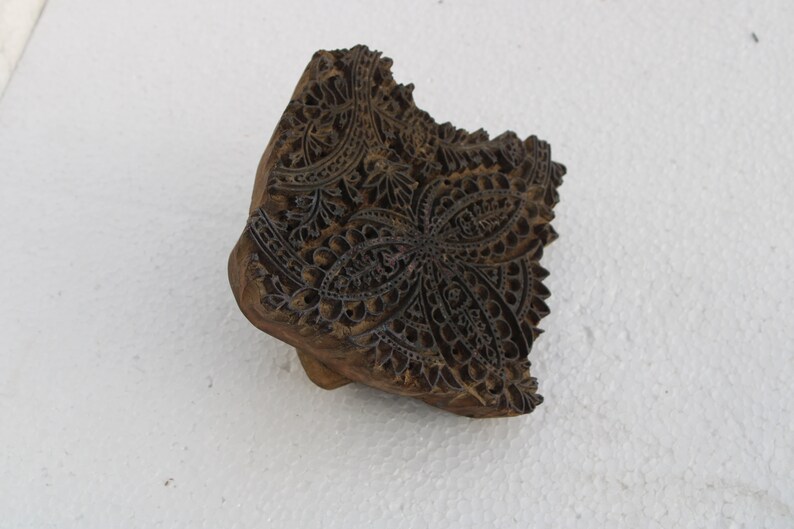 May include: A wooden block printing stamp with a detailed floral design. The stamp is carved with intricate patterns and is ready to be used for textile printing.