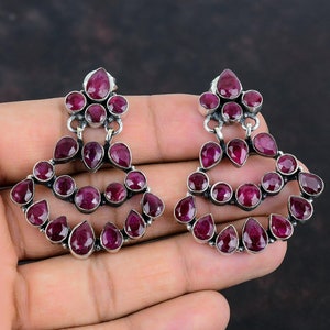 May include: A pair of silver earrings with multiple tiers of pink gemstones. The earrings are in the shape of a teardrop and have a delicate design.