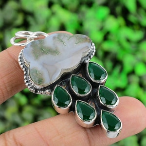 May include: A silver pendant featuring a cloud-shaped moss agate stone at the top and six faceted, pear-shaped green onyx stones hanging below. The metal setting has a beaded border detail and a circular bail at the top for a necklace chain.
