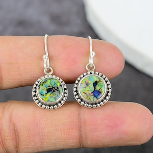 May include: A pair of silver dangle earrings with round iridescent green, blue, and gold opal stones.