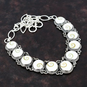 May include: A silver necklace with a chain and eight round white and brown abalone shell pendants.