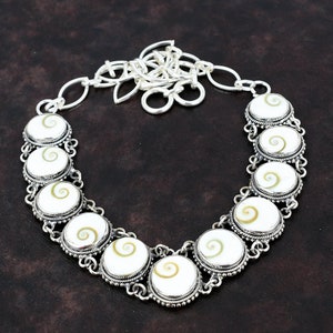 May include: A silver necklace with a chain and a pendant made of white shell with a brown spiral pattern.