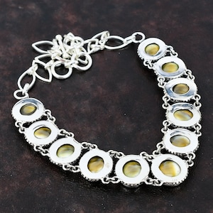 May include: A silver necklace with a chain and oval-shaped pendants featuring iridescent green and brown stones.