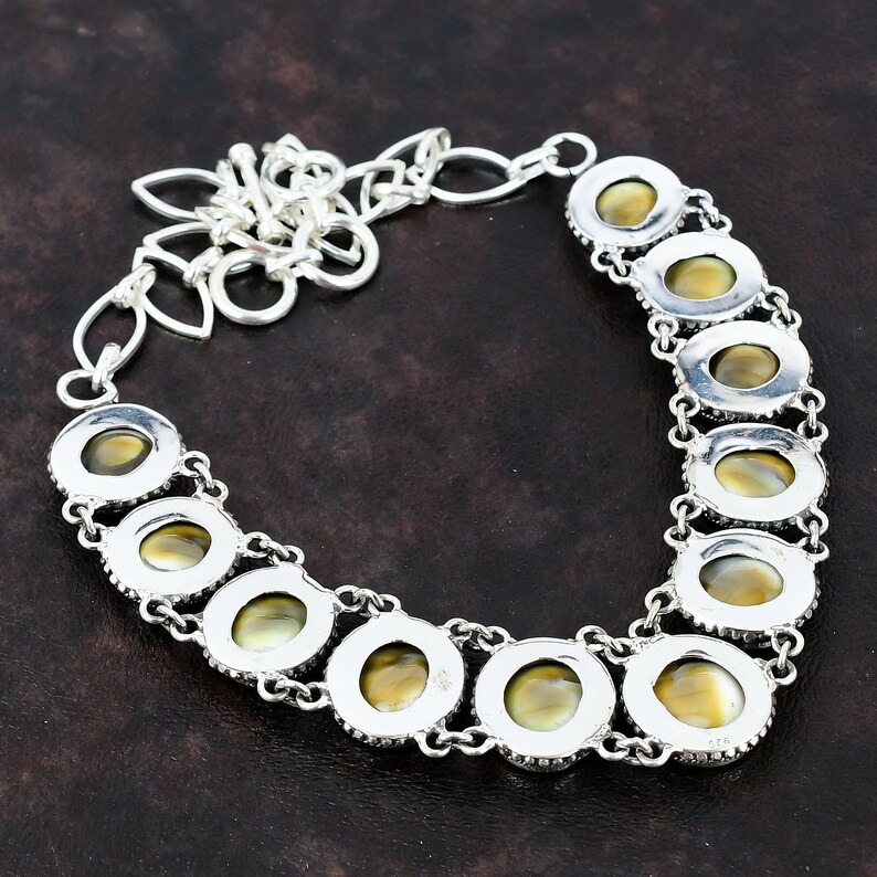 May include: A silver necklace with a chain and oval-shaped pendants featuring iridescent green and brown stones.