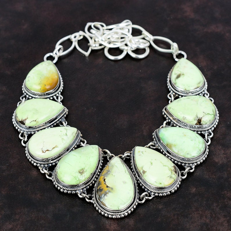May include: A silver necklace featuring a teardrop-shaped green gemstone pendant. The necklace has a chain with a lobster clasp.