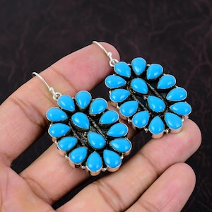May include: A pair of silver earrings with turquoise stones in a flower shape.