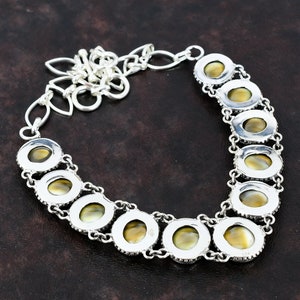 May include: A silver necklace with a chain and oval-shaped green and gold stones. The stones are set in silver bezels and have a textured surface.
