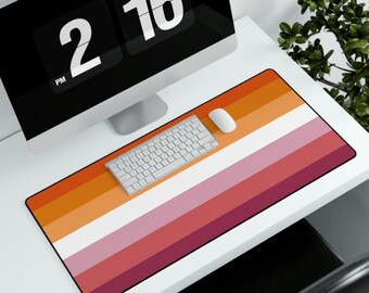 Puede incluir: Un tapete de ratón con temática de la bandera del orgullo lésbico con rayas naranja, rosa, blanco, rojo y burdeos. Un teclado blanco y un ratón de ordenador blanco están sobre el tapete de ratón.