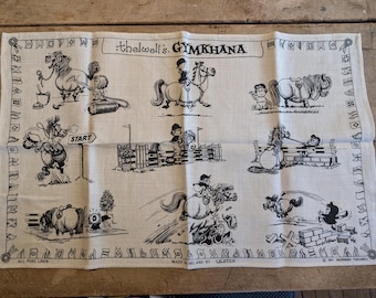 Könnte beinhalten: Cremefarbenes Leinentuch mit schwarz-weißen Cartoon-Illustrationen von Pferden und Reitern, die an einer Gymkhana teilnehmen. Der Text "thelwel's GYMKHANA" und "ALL PURE LINEN" sind auf dem Tuch aufgedruckt. Hergestellt in Irland von Ulster.