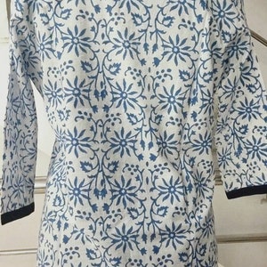 May include: A white cotton top with a blue floral print and a black collar.