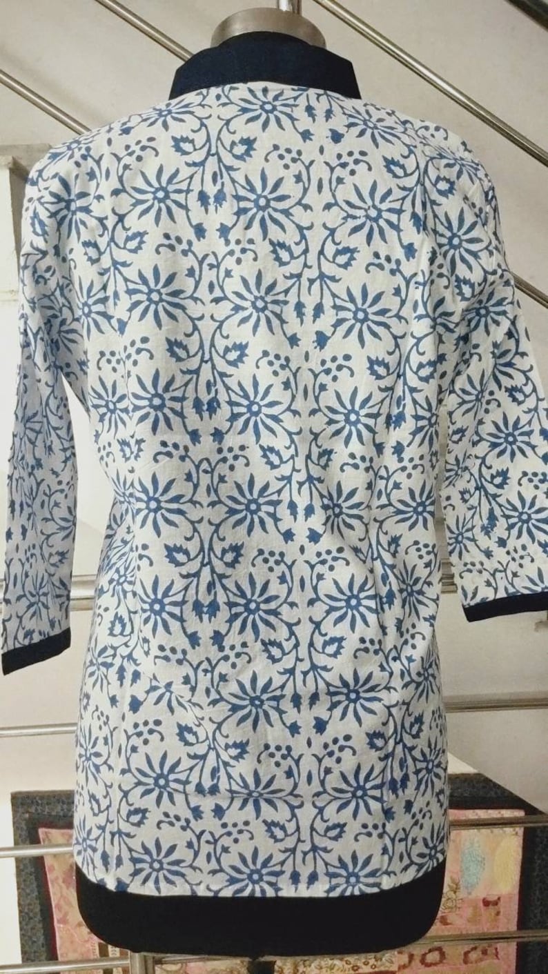 May include: A white cotton top with a blue floral print and a black collar.