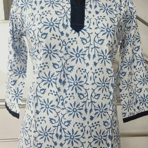 May include: White cotton tunic top with a blue floral print and a dark blue trim around the neckline and hem.