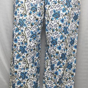 May include: White palazzo pants with a blue and green floral print. The pants have a wide leg and a relaxed fit.