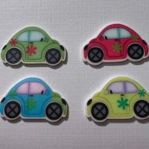 May include: Four colorful car-shaped buttons with flower designs. The cars are green, red, blue, and yellow. Each car has a black X on the wheels.