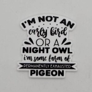 May include: Black and white sticker with the text "I'm not an early bird or a night owl, I'm some form of permanently exhausted pigeon."