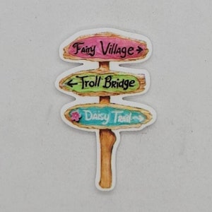 May include: A wooden signpost with three arrows pointing in different directions. The top arrow points right and says "Fairy Village". The middle arrow points left and says "Troll Bridge". The bottom arrow points right and says "Daisy Trail".