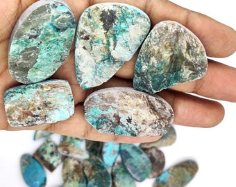 May include: A collection of raw, polished stones in shades of teal, brown, and gray. The stones vary in size and shape, with a mix of smooth and textured surfaces. Some stones have a prominent teal color, while others are more muted.