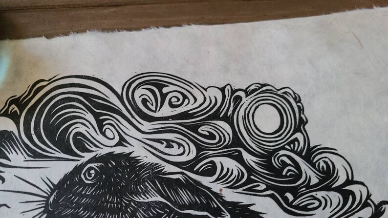May include: Black and white linocut print of a rabbit with swirling patterns around it.