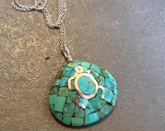 Puede incluir: Un collar de cadena de plata con un colgante de tortuga de turquesa y plata. La tortuga está hecha de piedras de turquesa en mosaico y tiene un contorno de plata.