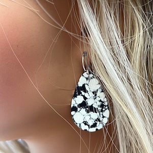 May include: Black and white teardrop-shaped earrings with a marbled pattern.
