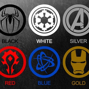 Pu&ograve; includere: Sei loghi circolari in nero, bianco, argento, rosso, blu e oro. Ogni logo presenta un design diverso, tra cui un ragno, una stella, la lettera A, un simbolo stilizzato, una rete di linee e una maschera di Iron Man. I colori sono etichettati sotto ogni logo.