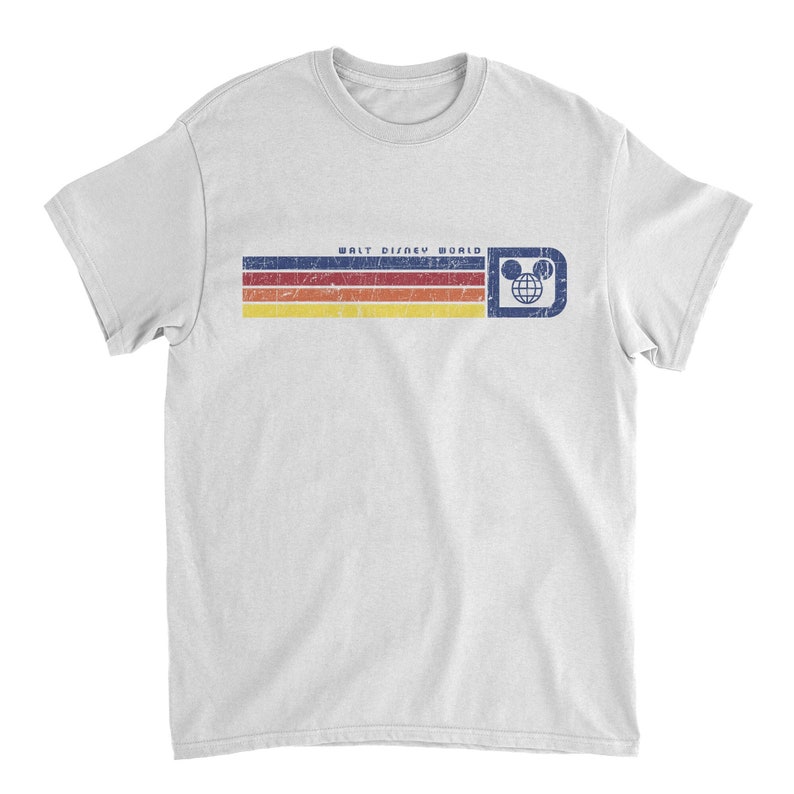 May include: White t-shirt featuring a retro design with horizontal stripes in blue, red, orange, and yellow. The text "WALT DISNEY WORLD" is above the stripes, with a Mickey Mouse head logo on the right. A vintage-style graphic tee.