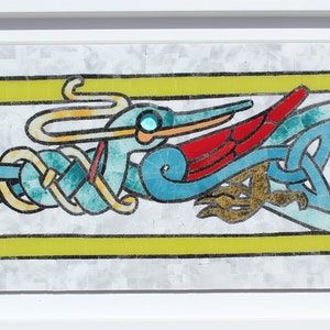 Puede incluir: Una obra de arte en mosaico que representa un pájaro estilizado con colores rojo, azul y amarillo. El pájaro está rodeado de intrincados patrones de nudos.