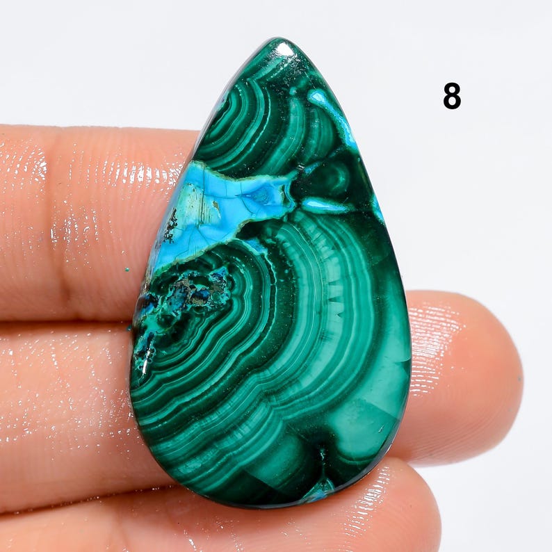 May include: A green and blue gemstone cabochon with a teardrop shape. The stone has a swirling pattern of green and blue.