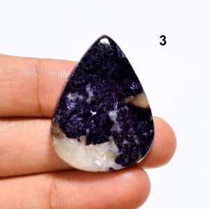 May include: A purple and white gemstone cabochon with a teardrop shape. The stone has a mottled pattern and is set in a silver bezel.