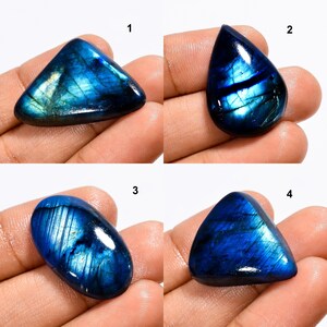 May include: Four labradorite gemstone cabochons in different shapes and sizes. The cabochons are a deep blue with iridescent flashes of green and gold.