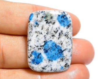 May include: A smooth, polished, rectangular blue and white stone with a speckled pattern. The stone has a light blue, white, and black color scheme.