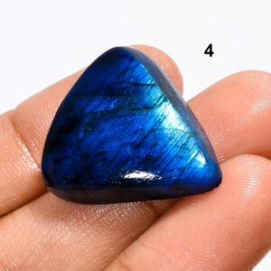 May include: A triangular, iridescent blue labradorite gemstone with a smooth, polished surface. The gemstone is approximately 2 inches long and 1.5 inches wide.