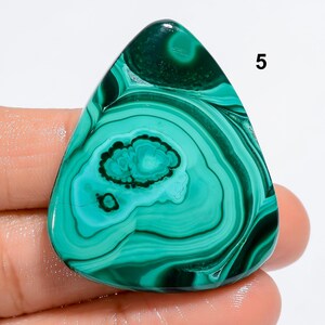 May include: A green, blue, and white malachite cabochon with a triangular shape. The stone has a swirling pattern and is approximately 2 inches in length.