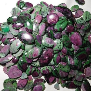 Pode incluir: Um grande monte de pedras preciosas ovais de cor verde e rosa. As pedras têm um aspecto manchado com redemoinhos verdes e rosas.