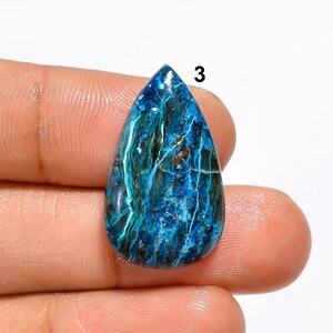 Pu&ograve; includere: Una pietra preziosa cabochon a forma di lacrima con un motivo marmoreo blu, verde e marrone. La pietra &egrave; lunga circa 2,5 cm e larga 1,5 cm.
