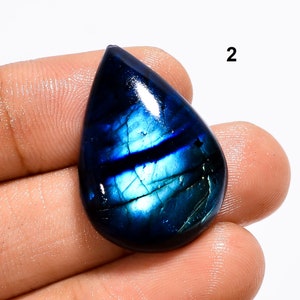 May include: A teardrop-shaped blue labradorite gemstone cabochon with iridescent flashes of green and blue.
