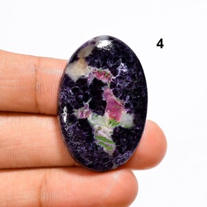 May include: Oval shaped cabochon gemstone with a purple, pink, white and green pattern. The stone is set in a silver ring.