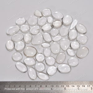 Op de afbeelding: Een verzameling van heldere kwarts cabochons, variërend in grootte van ongeveer 2,5 tot 3,8 cm in diameter. De cabochons zijn glad en gepolijst, met een doorschijnende uitstraling.