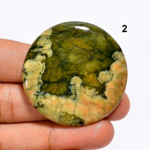 May include: A round, green and yellow, polished, cabochon gemstone with a unique, swirling pattern. The stone has a smooth, glossy finish.