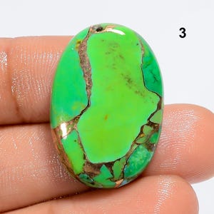May include: Green and copper oval cabochon gemstone with a marbled pattern.