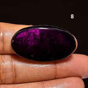May include: Oval-shaped purple gemstone with a dark, almost black, background and a shimmery, iridescent purple hue. The gemstone is set in a cabochon cut.