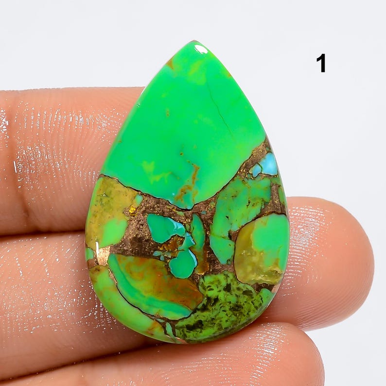 May include: A green, blue, and brown turquoise cabochon with a teardrop shape. The stone has a unique pattern of swirls and veins.