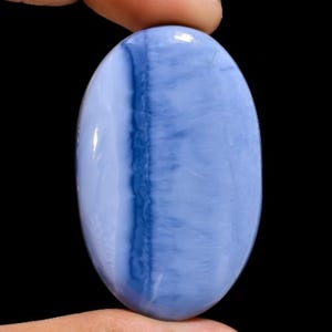 May include: A blue and white oval cabochon opal gemstone with a banded pattern. The opal is smooth and polished.