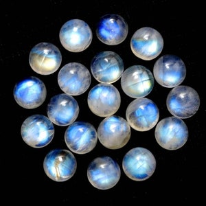May include: A collection of round, iridescent moonstone cabochons. The stones are a pale blue-white color with a shimmering, opalescent sheen.