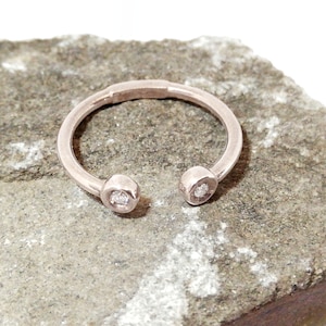 May include: A silver ring with two small diamonds set in the ends of the band.
