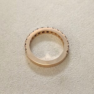 以下が含まれることがあります： ローズゴールドのバンドリングに、小さなダイヤモンドが並んだリングです。