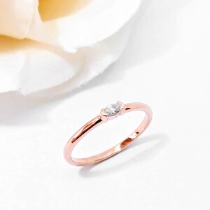 May include: A delicate rose gold band ring with a single marquise-shaped diamond.