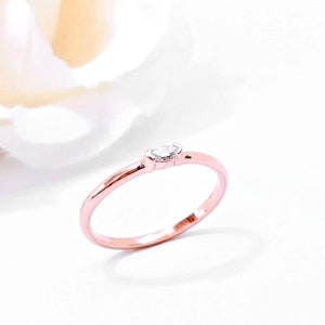 May include: A delicate rose gold band ring with a single marquise-shaped diamond set in the center.