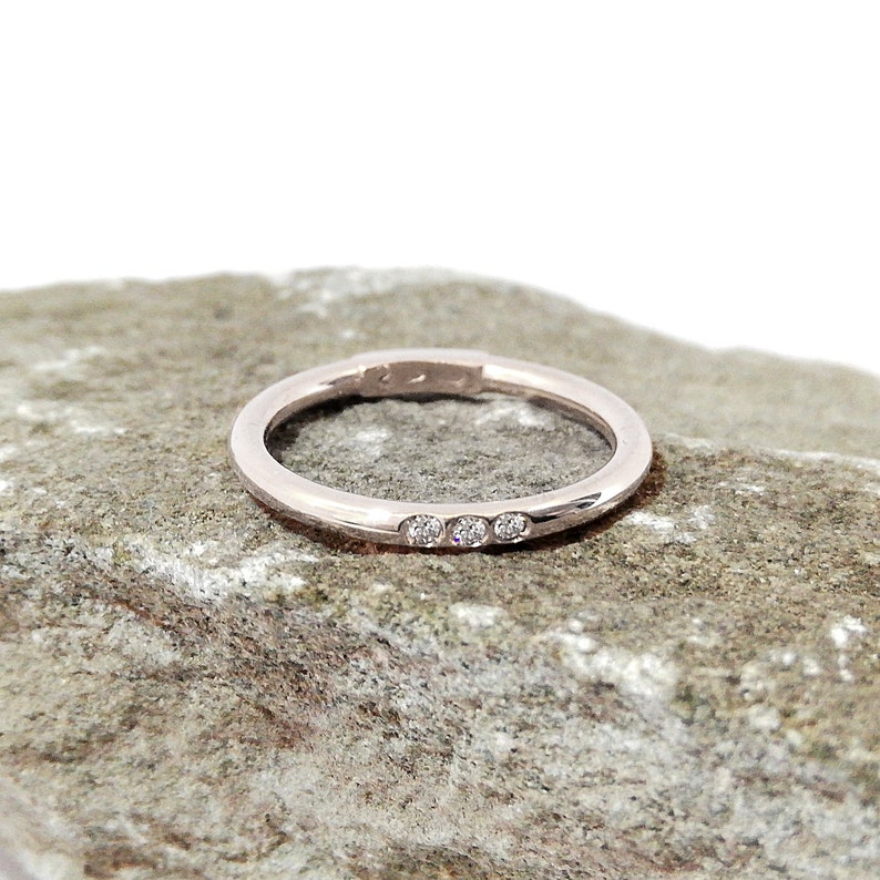May include: A thin, silver band with three small diamonds set in a row.